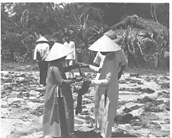 Bits of tattered clothing, sandals and slippers are examined by South Vietnamese women who lost relatives in the 1968 Huế massacre