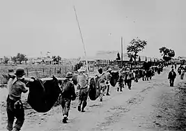 Soldiers carry bodies after the Bataan Death March (1942).  About 20,000 Filipino POWs and 1,600 Americans died