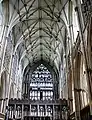 The interior (inside) of York Minster shows clustered columns, vaulted roof, traceried window, ancient stained glass and a stone screen.