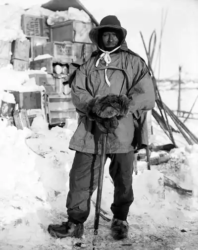 Photo of a man in cold weather gear posing in front of stacked supplies