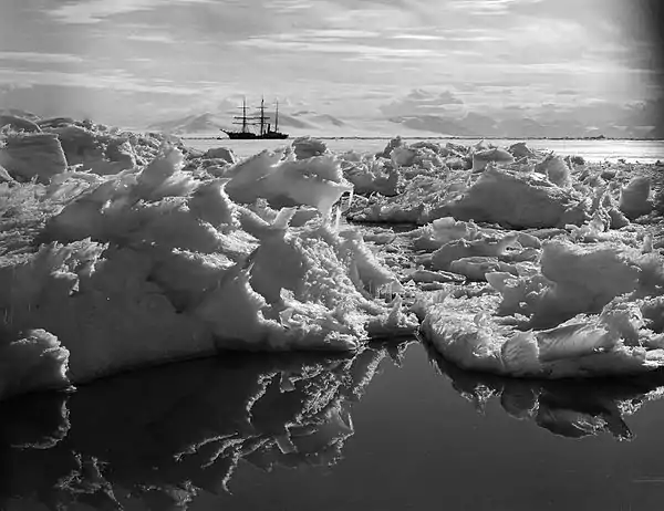 Photo of a distant ship across jagged ice and some open water