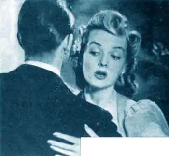 Woman embracing a suited man, while looking with concern at the dandruff on his shoulder.