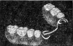 Black and white photograph of two strips of four teeth held together by wire.