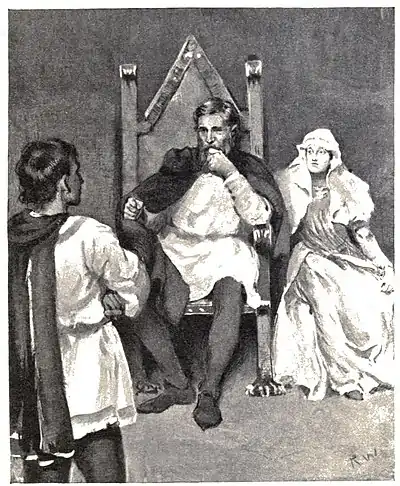 A man sitting on a large chair, a woman sitting beside him and another man standing in the foreground—in front of the sitting pair with his back to the viewer.