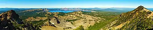 A panorama shot displays Crater Lake in the center background, with mountains in the foreground on the left and right