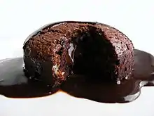 A chocolate cake cut open with chocolate sauce running out