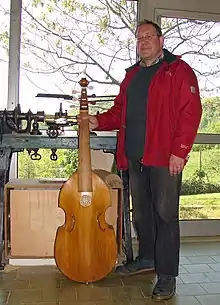 A man standing, holding a viol