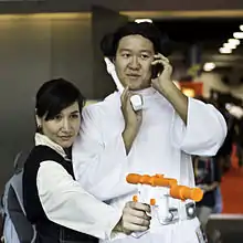 Photograph of two Star Wars cosplayers: A woman dressed as the male character Han Solo and a man dressed as the female character Princess Leia.